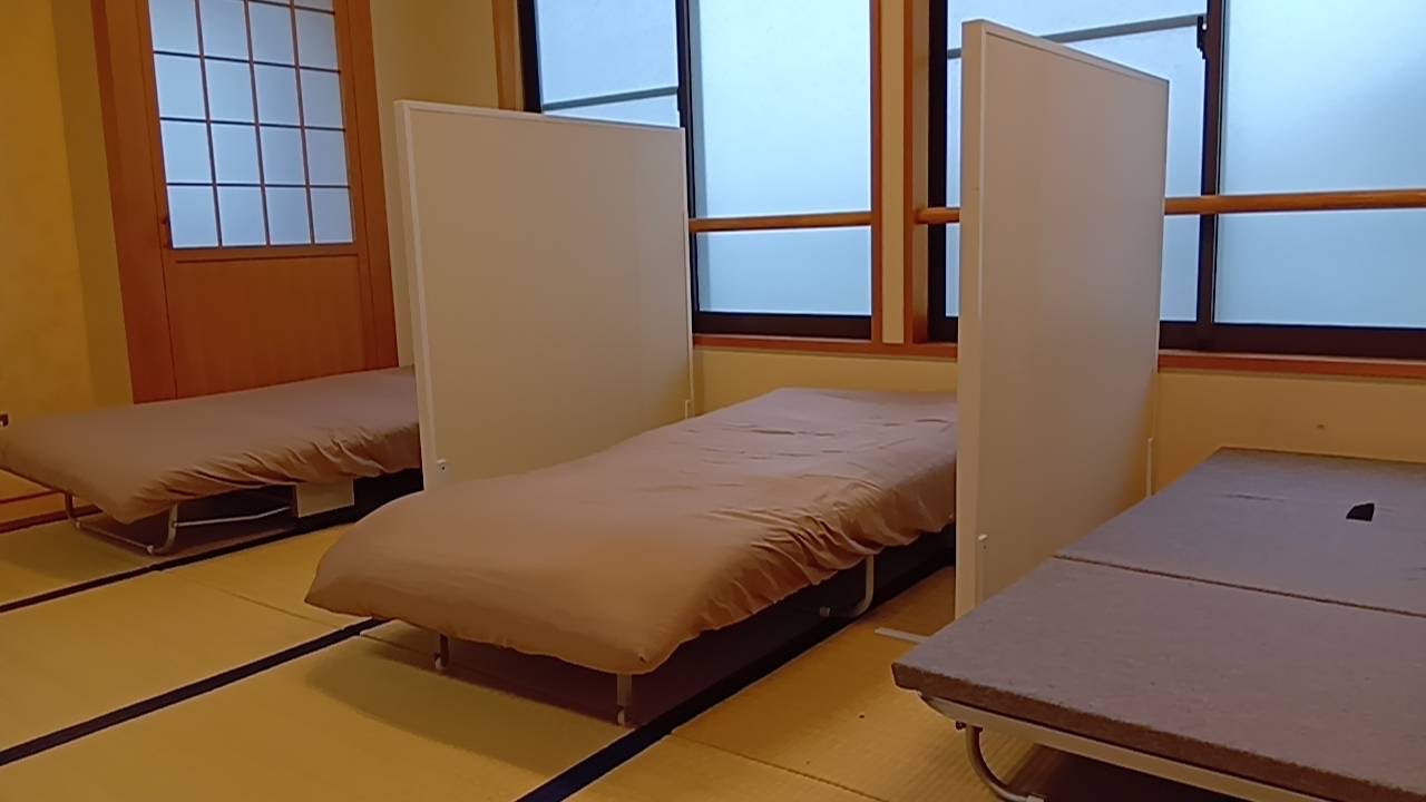 畳の部屋に並ぶベッドと間仕切り